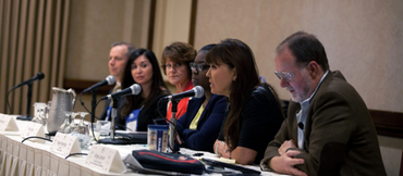 panel of speakers at a table with microphones